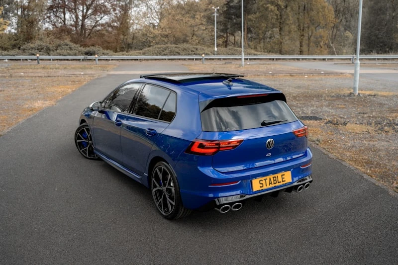 Blue Volkswagen Golf R from the rear three-quarter on an empty UK road