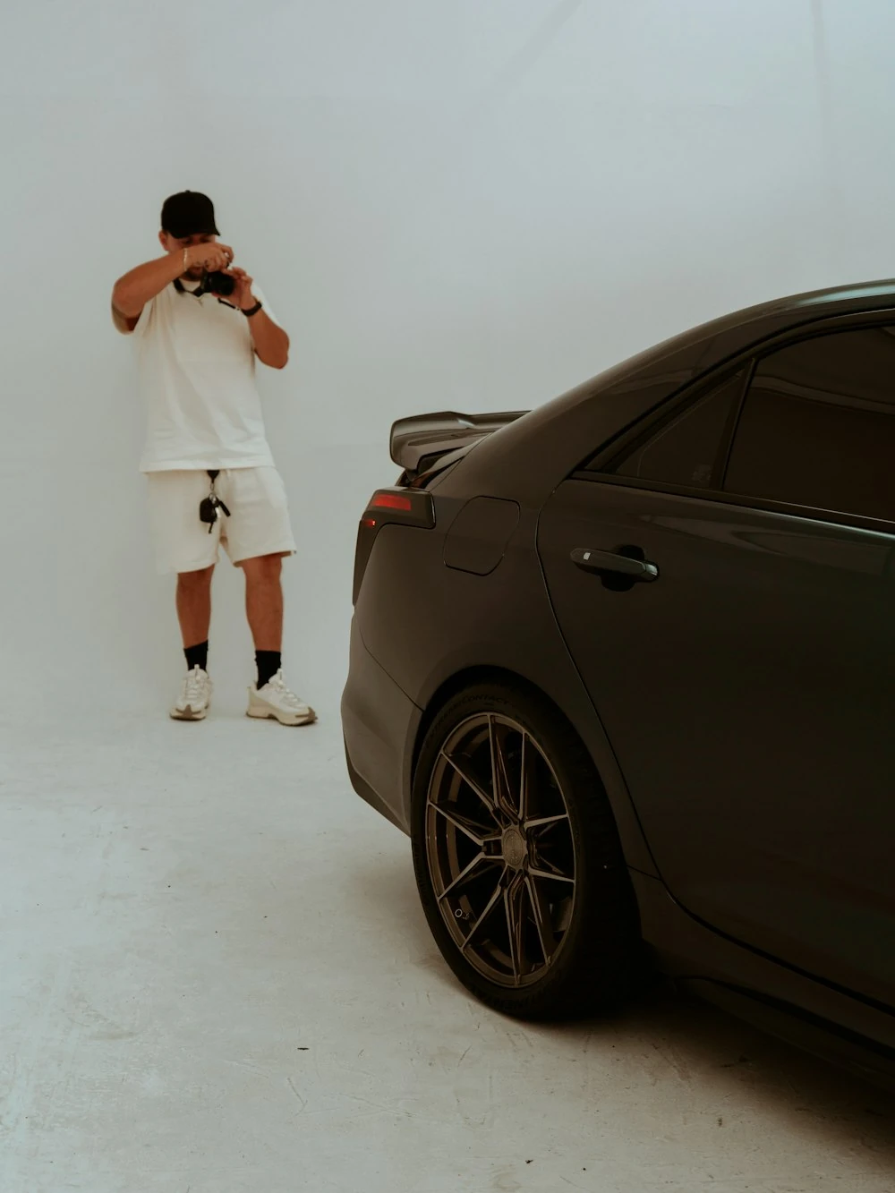 Photographer shooting a black sports car in a studio